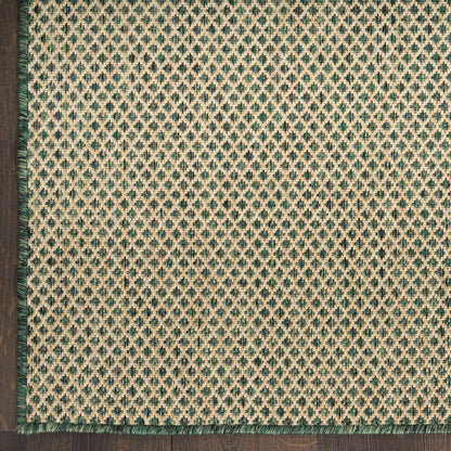 Beige woven rug with teal diamond lattice pattern & dark green fringe trim along left & bottom edges on wood floor