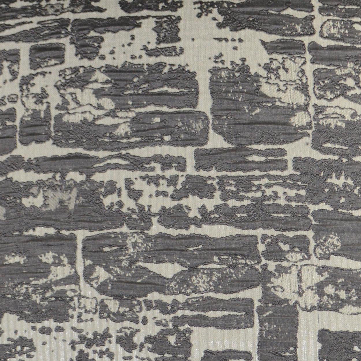 Charcoal gray abstract pattern on a light beige, distressed-texture pillow.