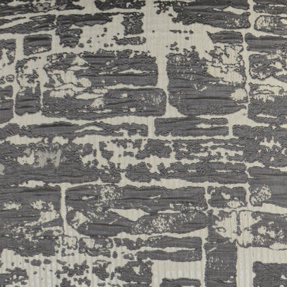 Charcoal gray abstract pattern on a light beige, distressed-texture pillow.