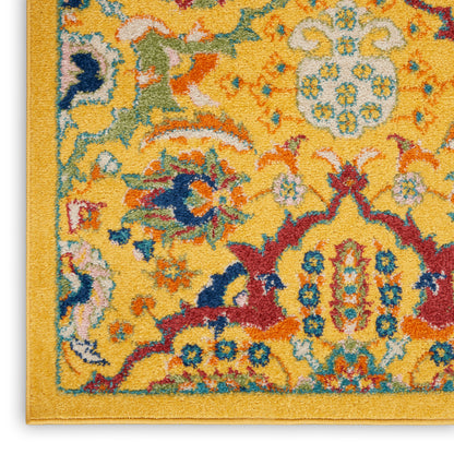 Corner of a yellow ornate rug with blue, red, green floral motifs and a gold border.
