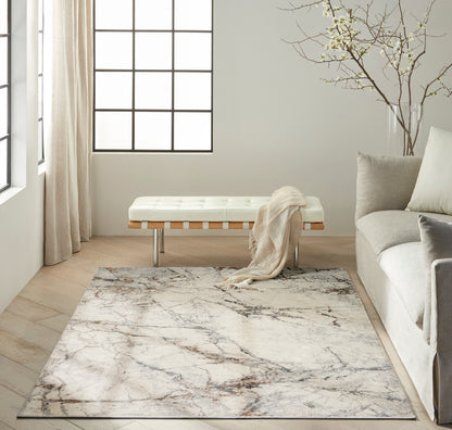 Modern neutral living room with ivory tufted bench, wood slats and metal legs, marble-pattern rug, beige sofa & throw.