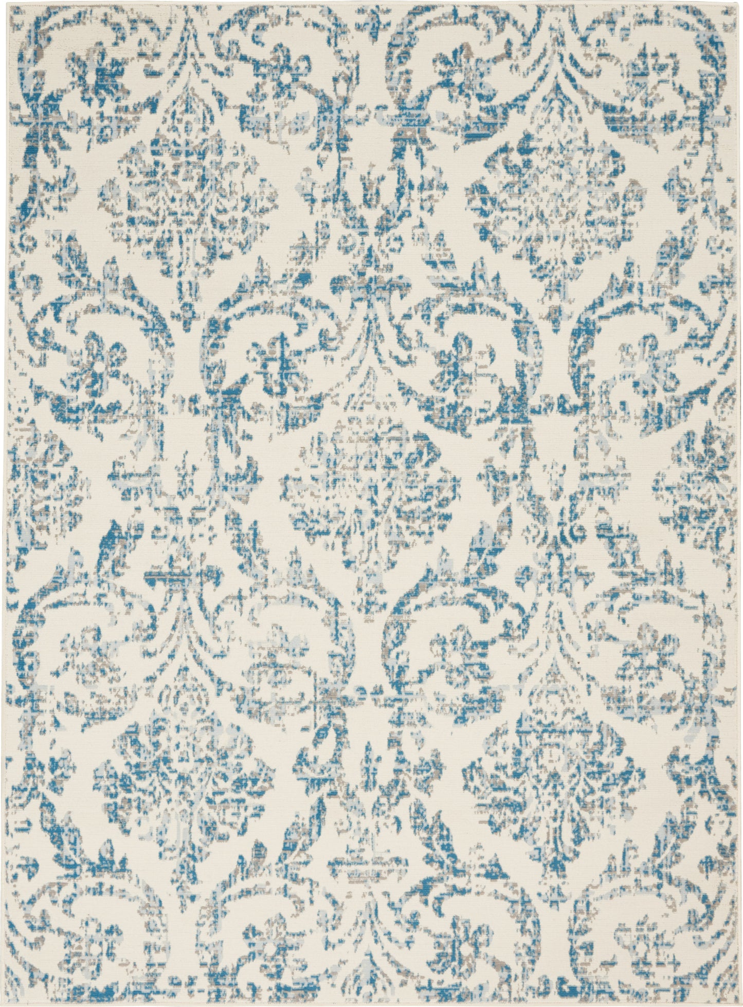 Blue damask patterned area rug on cream background; distressed vintage ornate motif.