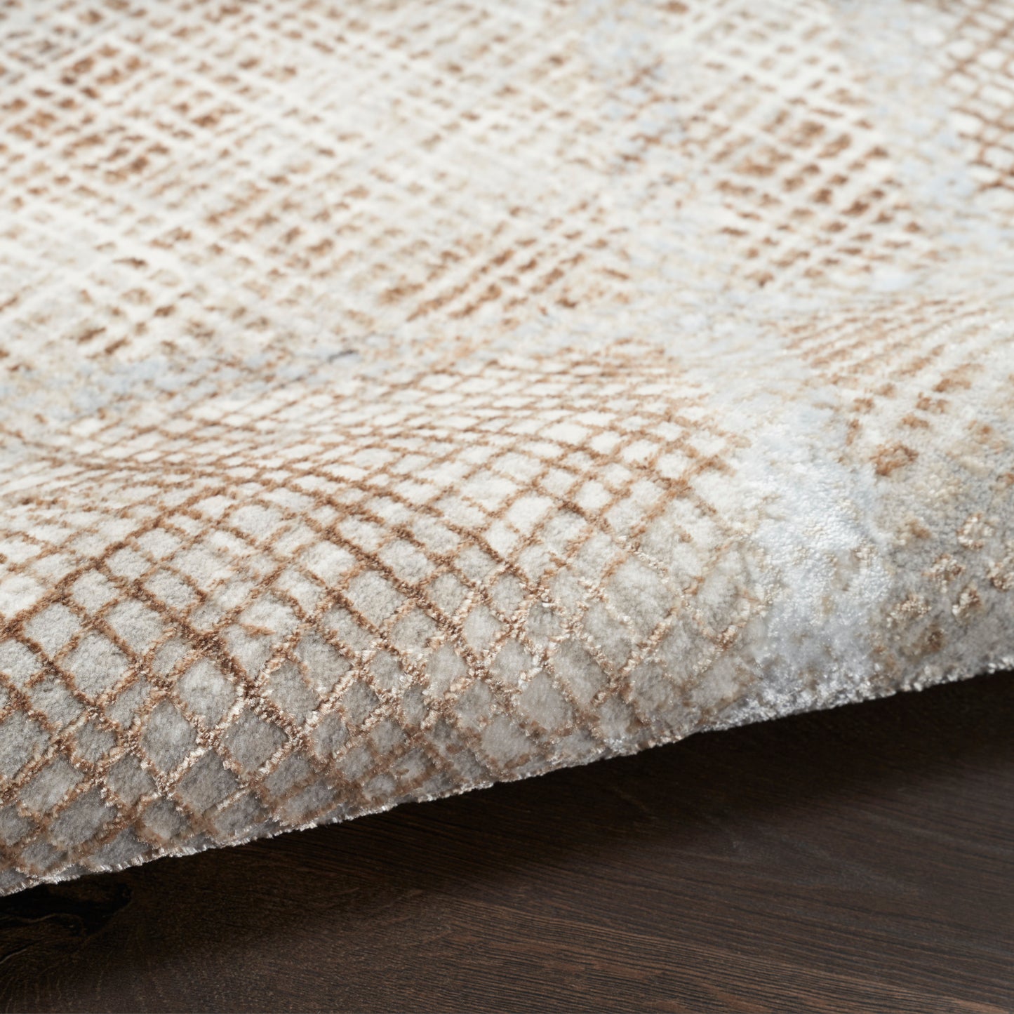 Beige and ivory rug with a subtle tan lattice pattern and soft plush texture on a dark wood floor