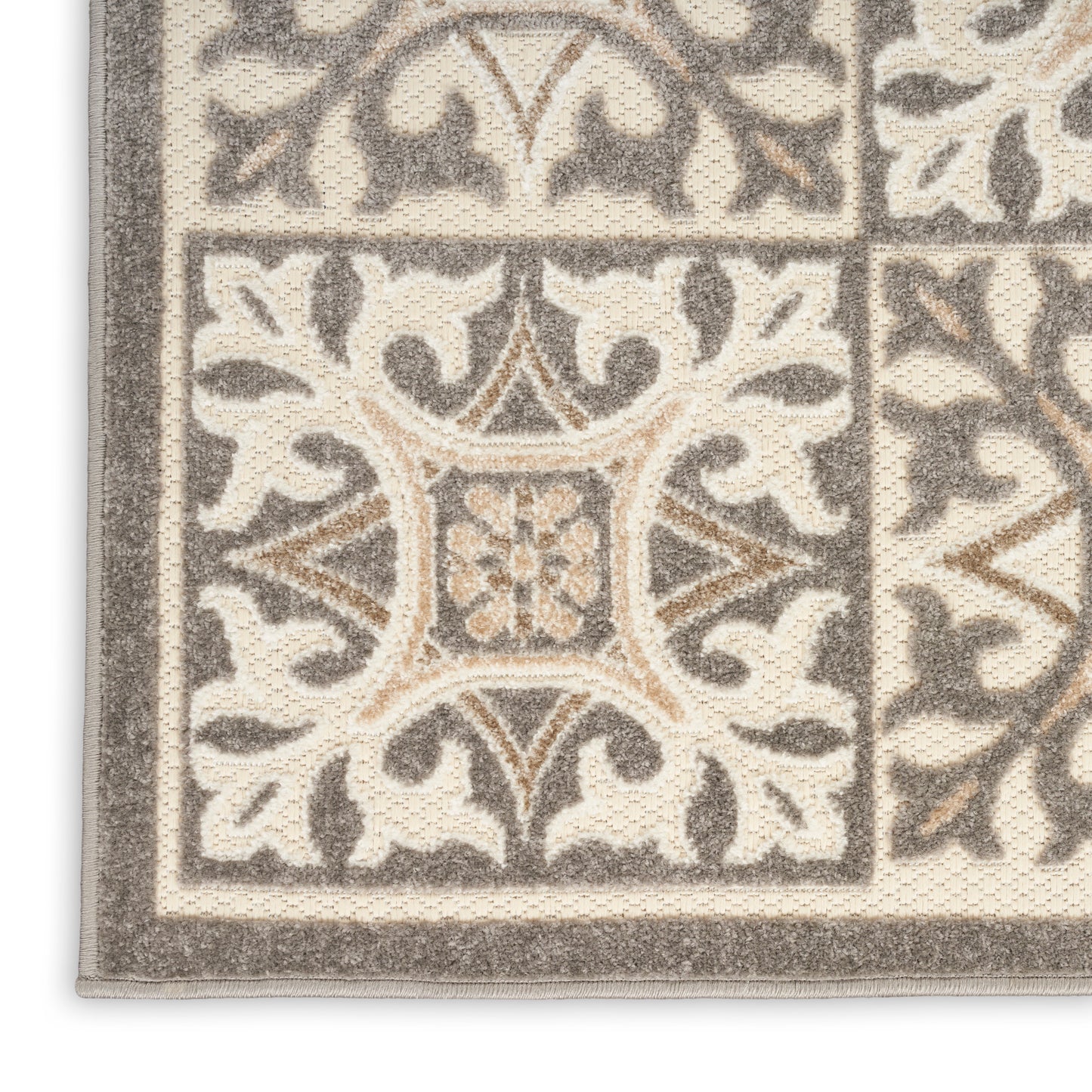 Beige and gray ornate rug corner with tile-like blocks, scrolling floral motif, and thick border.