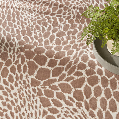 Brown giraffe-pattern rug with white spots; green fern in a gray pot sits on the right.