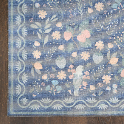 Blue floral area rug with scalloped border, pink and white flowers, green leaves and a central bird motif on a wooden floor.