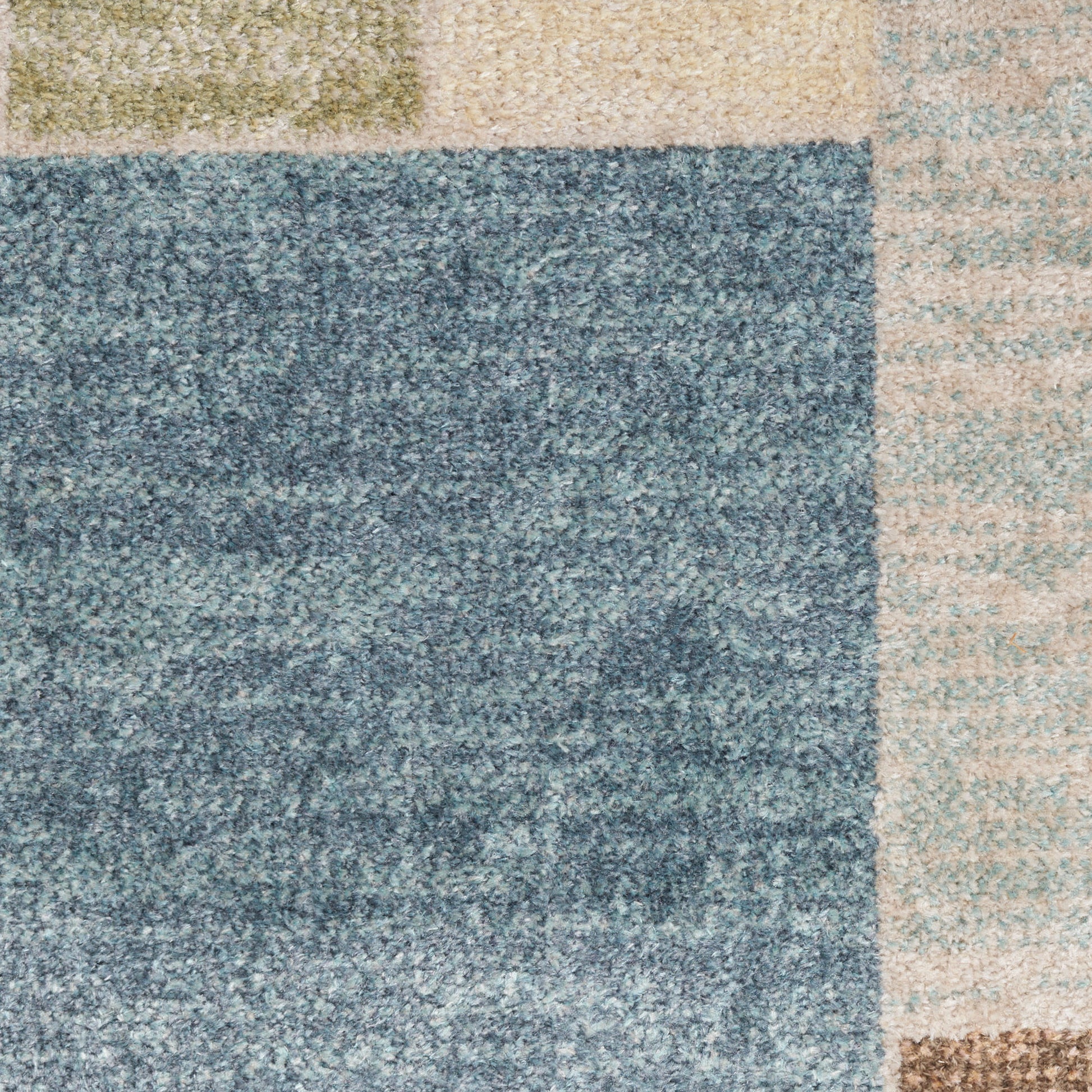 Patchwork shag rug in blue-gray, olive green, beige and tan blocks with a soft textured pile.