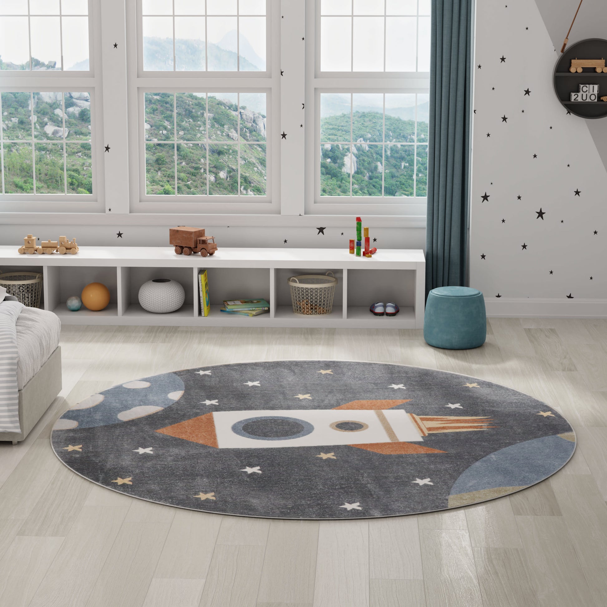 Circular grey rug with a rocket design and stars; kid's playroom with light wood floor, white shelving, and large windows.