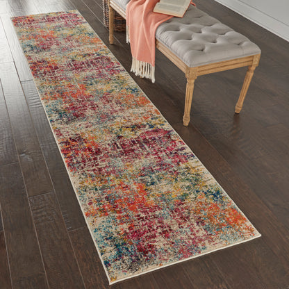 Long multicolor abstract runner rug on dark wood floor beside a tufted gray bench with a peach throw.