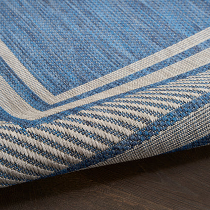 Blue woven rug with cream double border and braided blue-white edge; casual coastal style.
