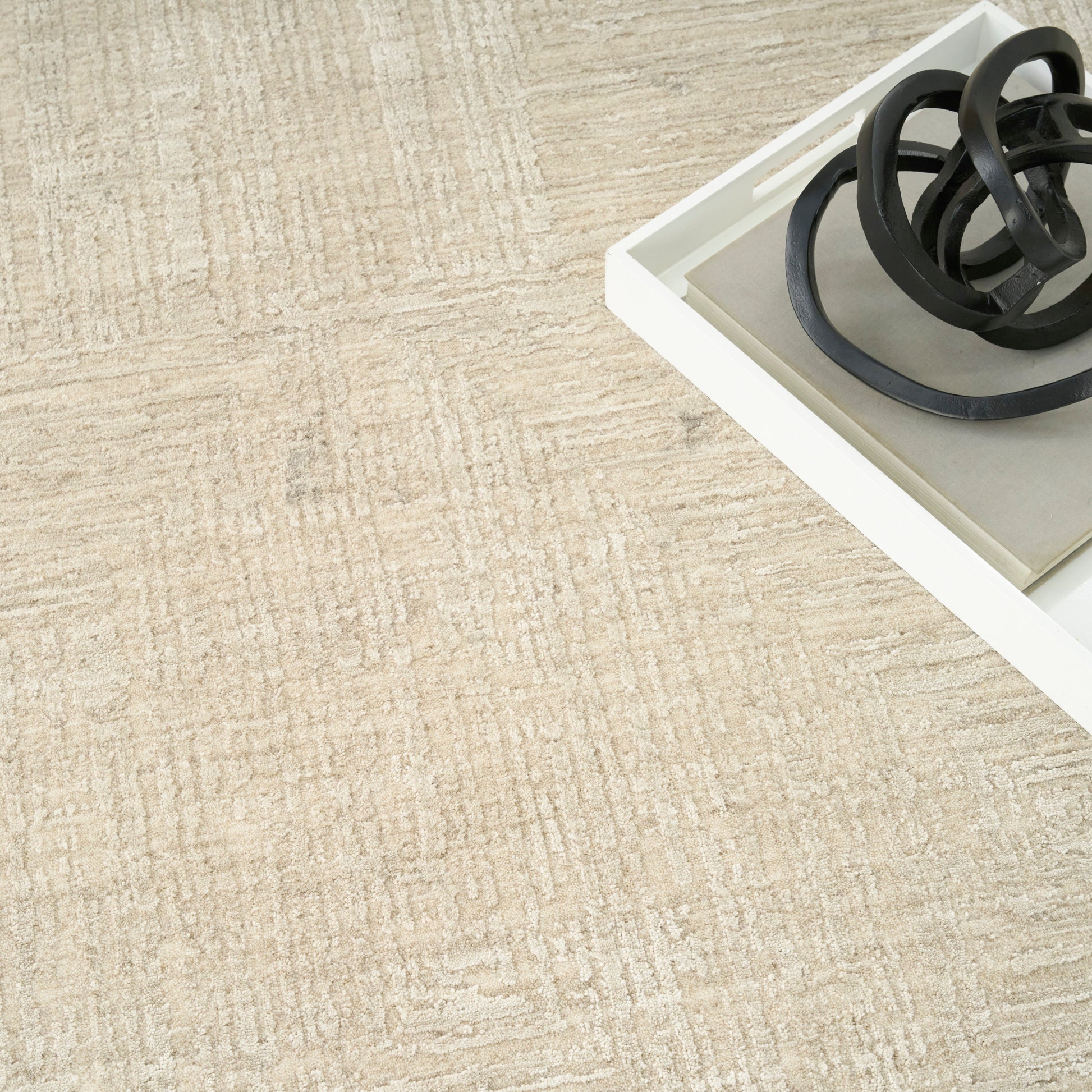 Beige textured rug with a white tray and black circular metal rings.