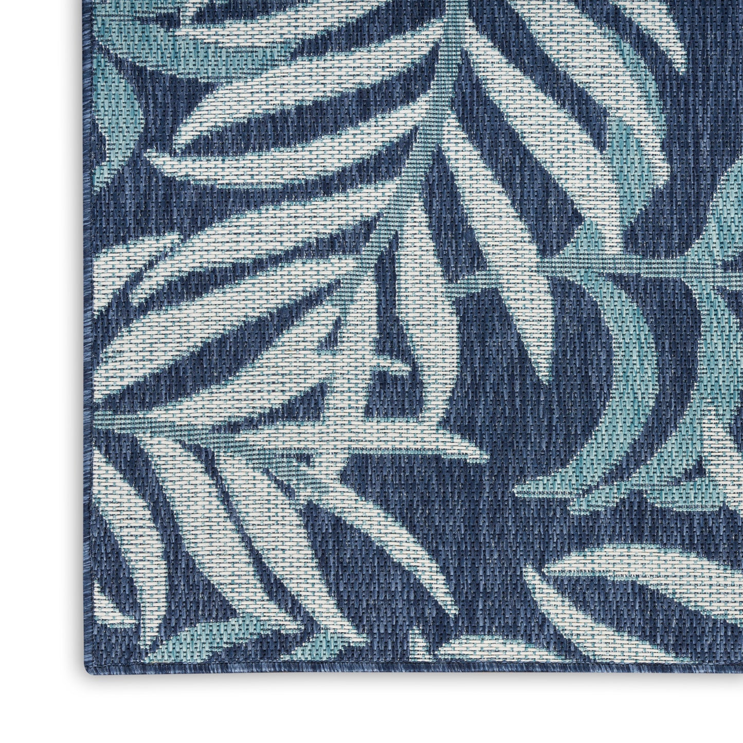 Rectangular woven rug with navy & teal tropical palm-leaf pattern and textured yarn.