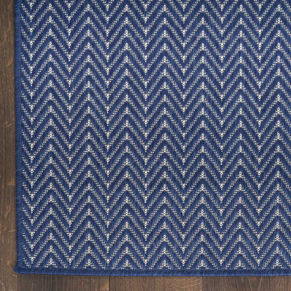 Blue chevron rug with white flecks in zigzag pattern on a dark blue field, blue fringe along the edge.
