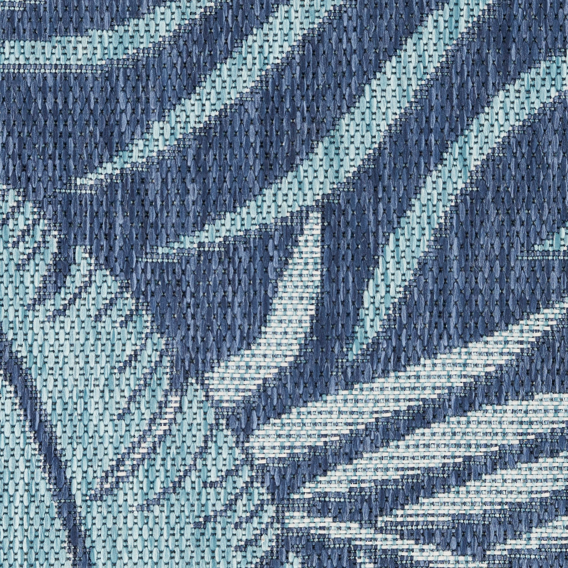 Close-up of woven fabric in navy and light teal with diagonal stripes and an abstract pattern; denim-like texture.