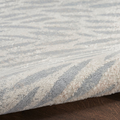 Blue and beige zigzag rug with textured pile, folded edge on dark wood floor.