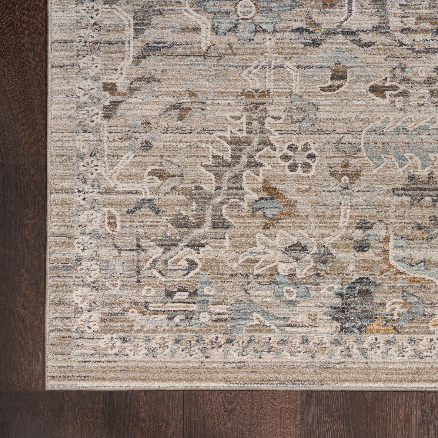 Beige distressed floral runner rug with blue-grey accents and a bordered edge on dark wood floor.