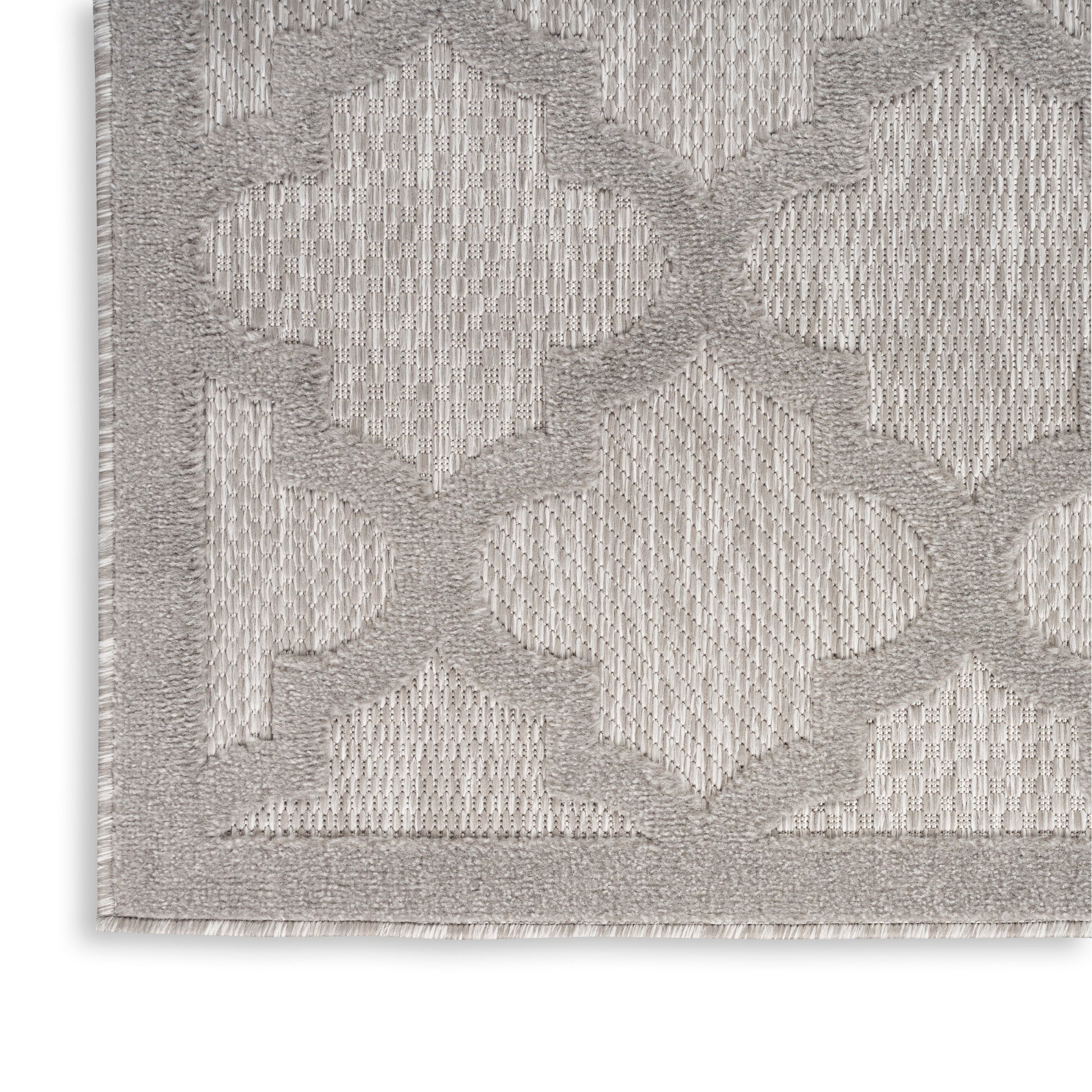 Light gray textured area rug with a raised geometric lattice/trellis pattern, bordered edge, close-up corner.