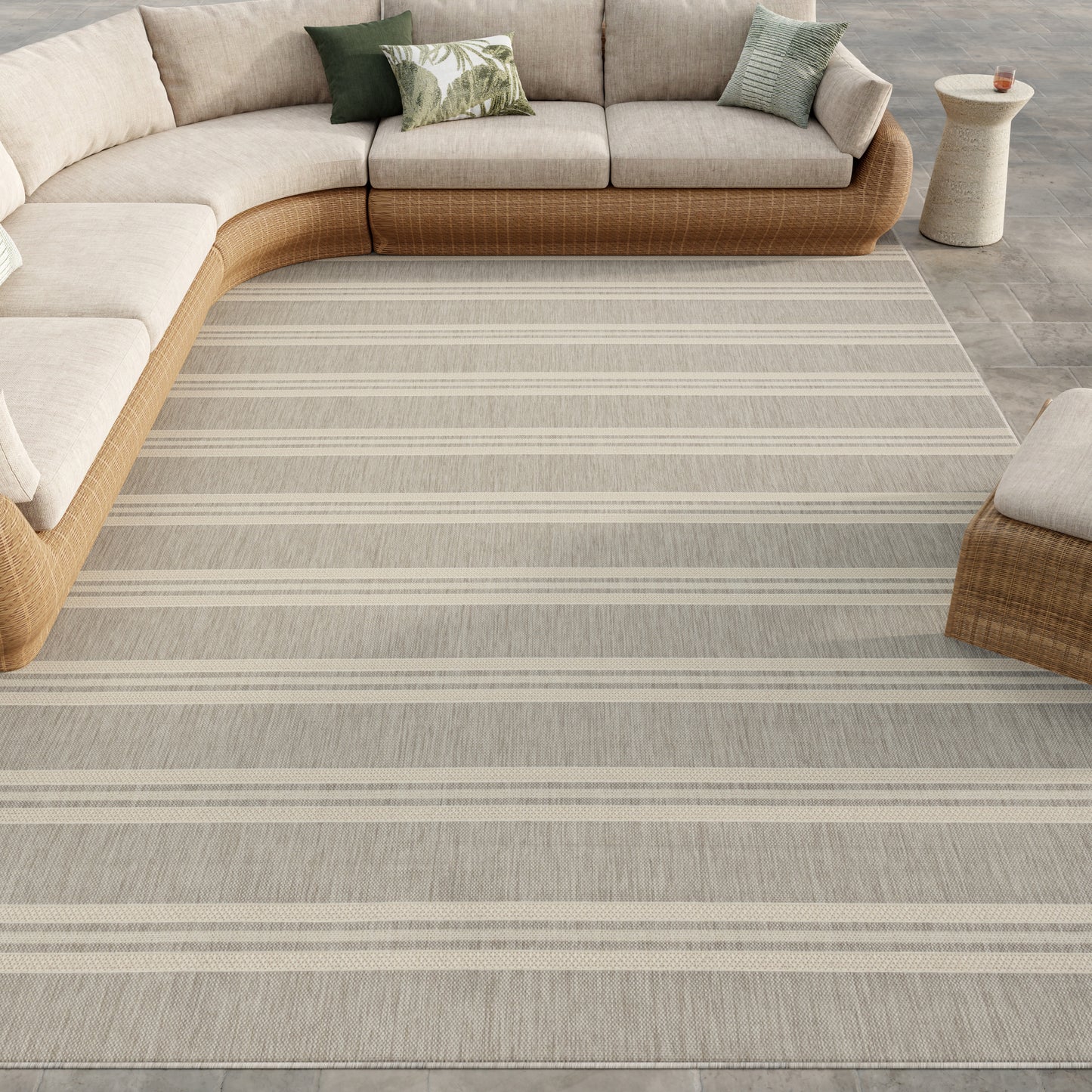 Curved beige sectional with a woven rattan frame on a light gray striped area rug in a modern living room.