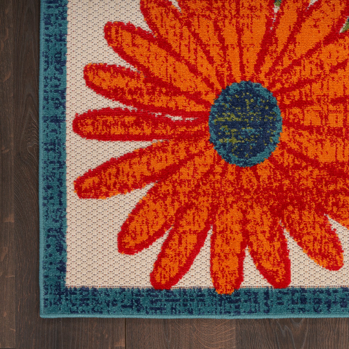 Vibrant orange daisy rug with teal border on beige background; woven texture, rectangular outdoor rug.