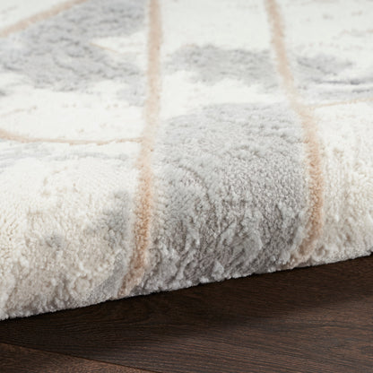 Close-up of a plush cream-gray area rug with tan stripes resting on dark wood floor.