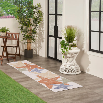 Outdoor runner rug with coral and blue starfish pattern on a porch with plants and glass doors.
