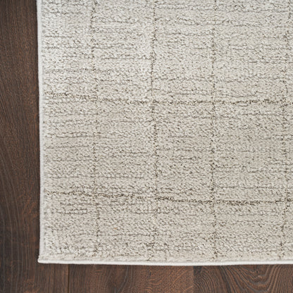 Beige rectangular area rug with subtle square grid pattern and soft textured loop-pile on dark wood floor.