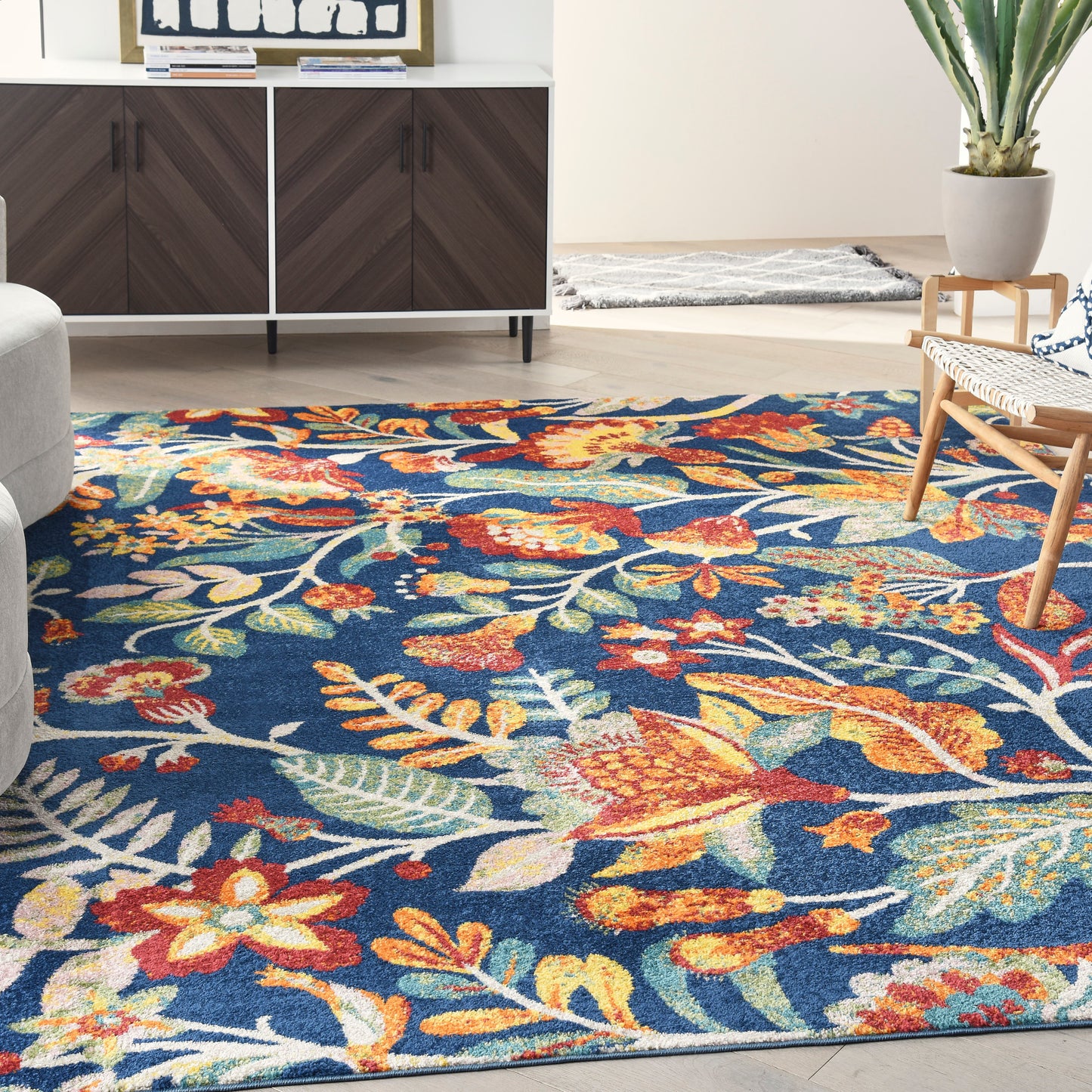 Blue floral area rug with orange & yellow flowers and green leaves in a modern living room.