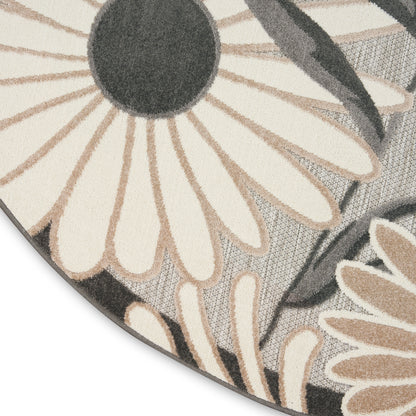 Round rug with oversized cream daisies and charcoal centers on a gray textured background.