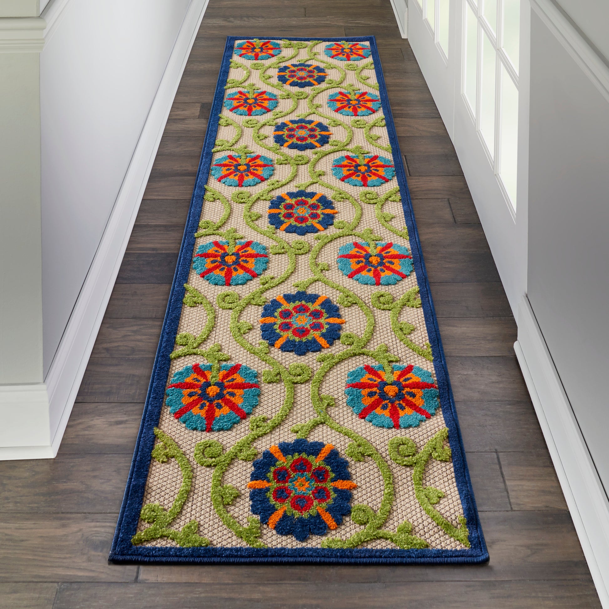 Long hallway runner rug with blue border, repeating circular blue and red floral medallions on beige with green vines.