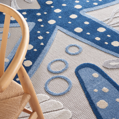 Close-up of a blue star-pattern area rug with white dots and circular shapes; wooden chair leg visible in the foreground.