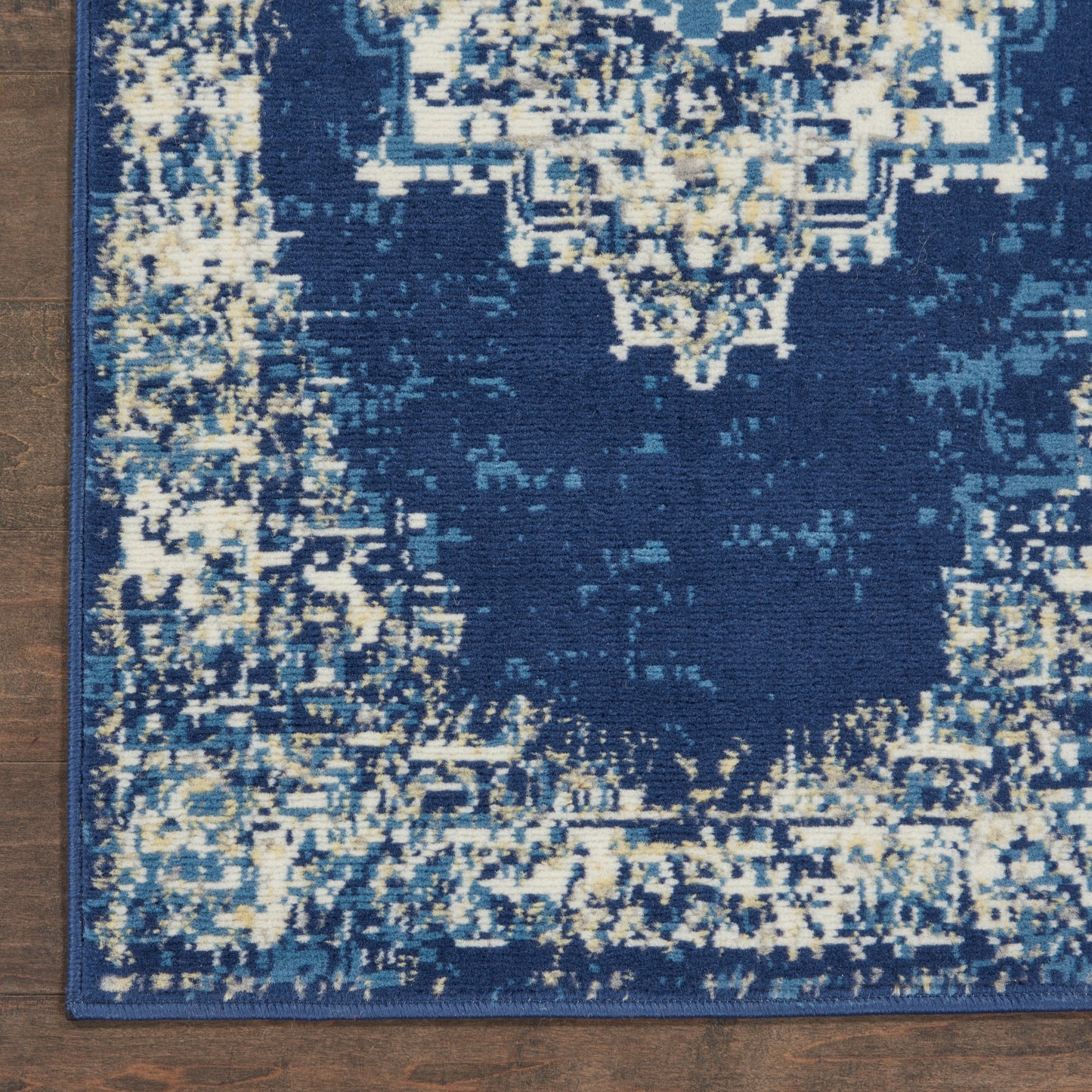 Distressed navy blue oriental area rug with cream and teal accents, central motif, bordered in blue on wood floor.