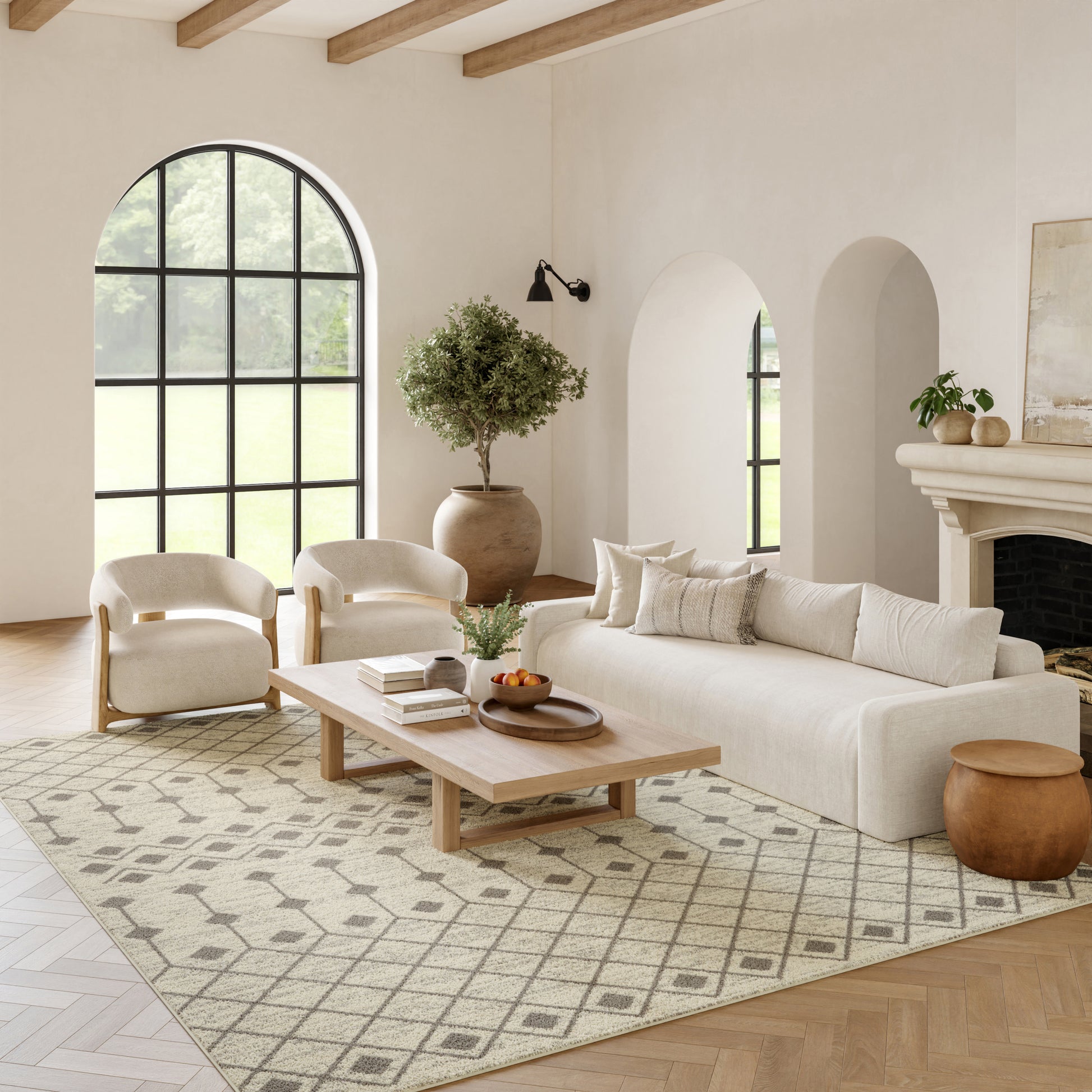 Bright living room with cream sofa and chairs, light wood coffee table, arched window, rug, potted tree, fireplace.