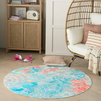 Round boho rug in turquoise, coral and teal with a white pattern, on light wood floor beside a wicker egg chair.