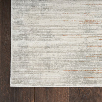Light gray and ivory textured rug with subtle beige and orange streaks and white fringe edge on dark wood floor.