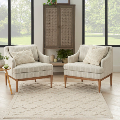 Pair of beige striped fabric armchairs with wooden legs, geometric rug, and a woven cabinet in neutral tones.