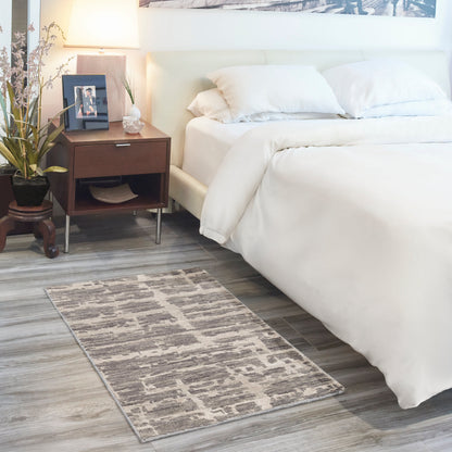 White upholstered bed with plush bedding, dark wood nightstand, lamp, framed photo, plant, and grey geometric rug.