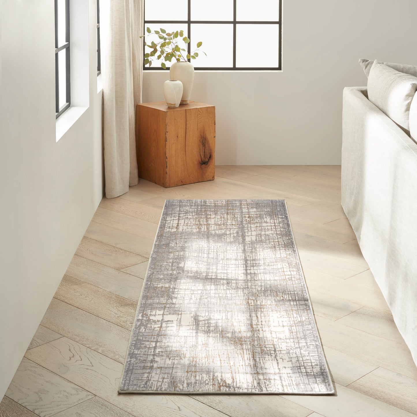 Textured gray distressed runner rug on light wood floor beside a gray sofa in a modern minimalist living room.