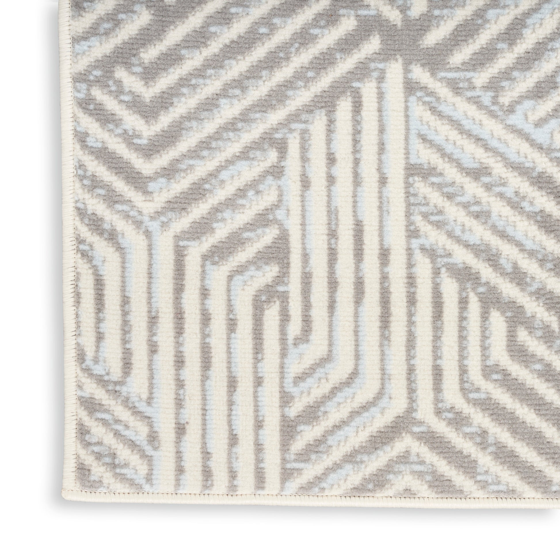Close-up of a beige/gray geometric rug with white linear maze pattern and cream border.