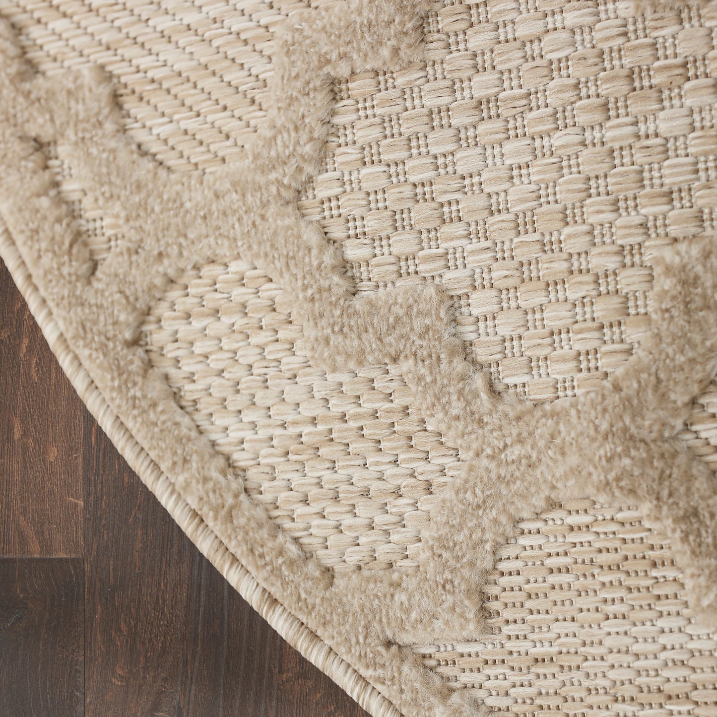 Beige woven rug with circular tufted motifs and natural jute texture on dark wood floor.