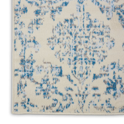 Cream rug with blue distressed floral medallion pattern; rectangular with fringe edges.