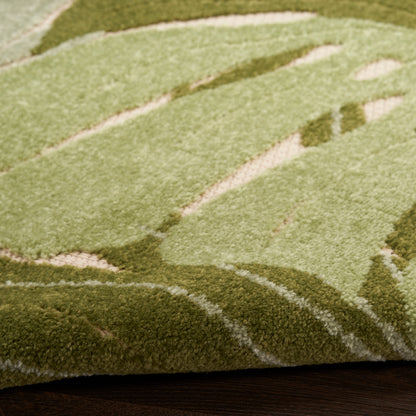 Close-up of a green outdoor rug with abstract light and dark olive patterns on a dark wooden deck, 6' x 9'.