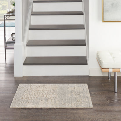Modern entryway with white staircase, dark brown treads, beige textured rug, white bench with chrome legs, & wall art.