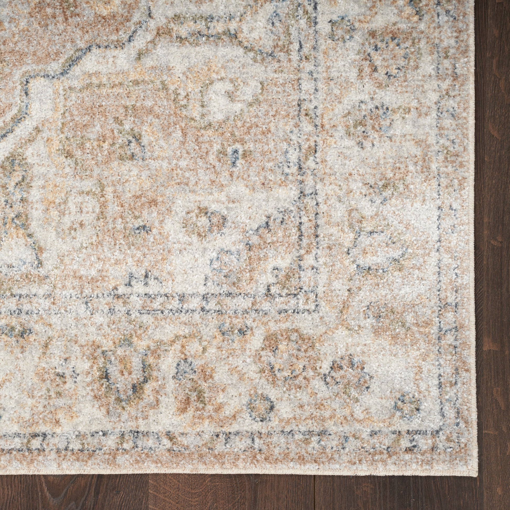 Rectangular beige oriental rug with blue-grey border and floral motifs on a dark wood floor.