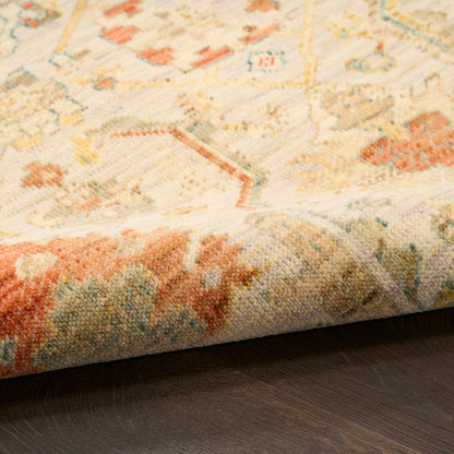 Close-up of a pastel oriental rug with cream, pale blue and orange patterns, folded edge on dark wood floor.
