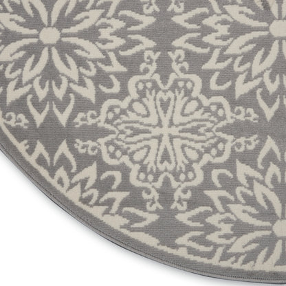 Round gray rug with white geometric floral/mandala motifs; soft woven texture, decorative for living room.