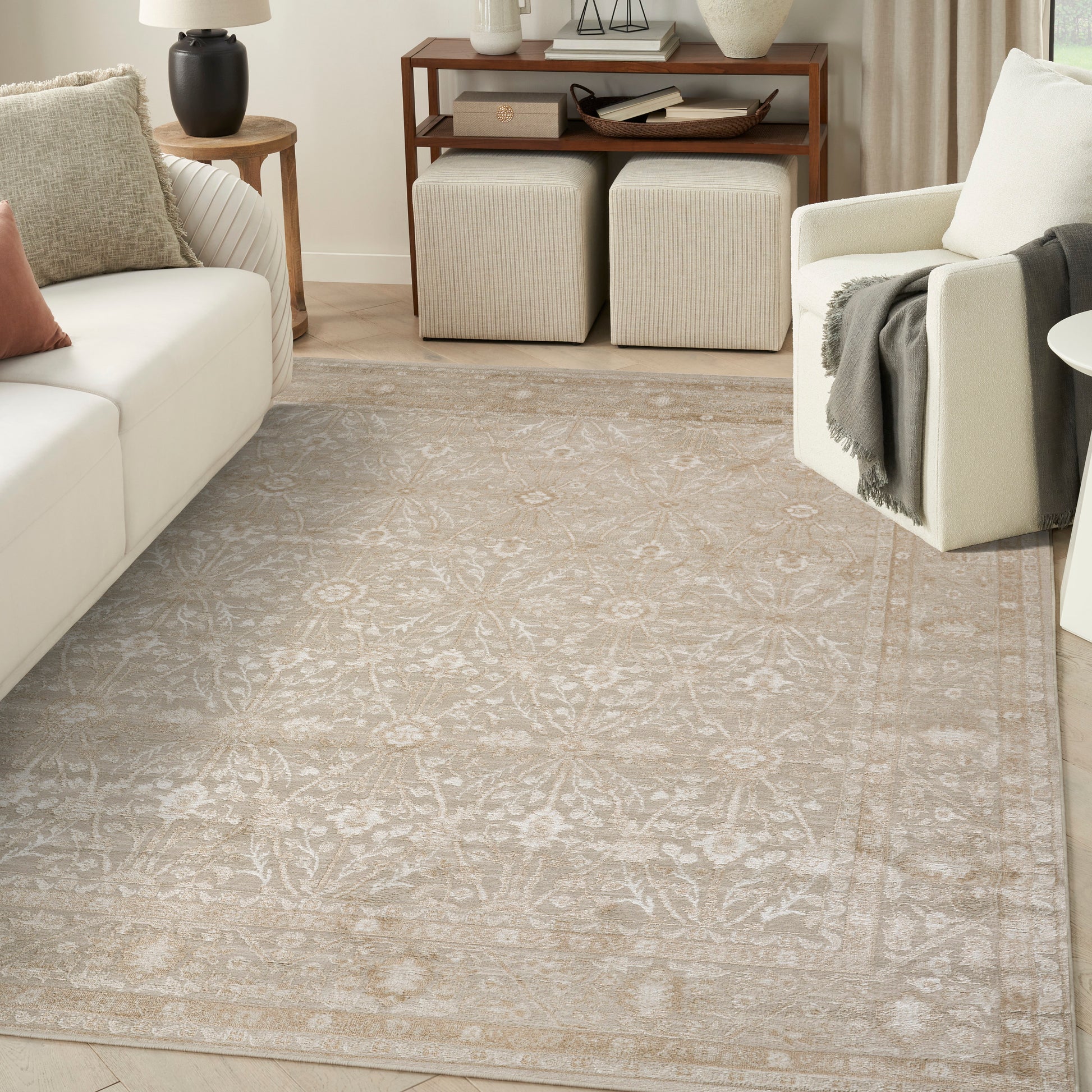 Cream area rug with muted ivory floral pattern and subtle border in a neutral living room.
