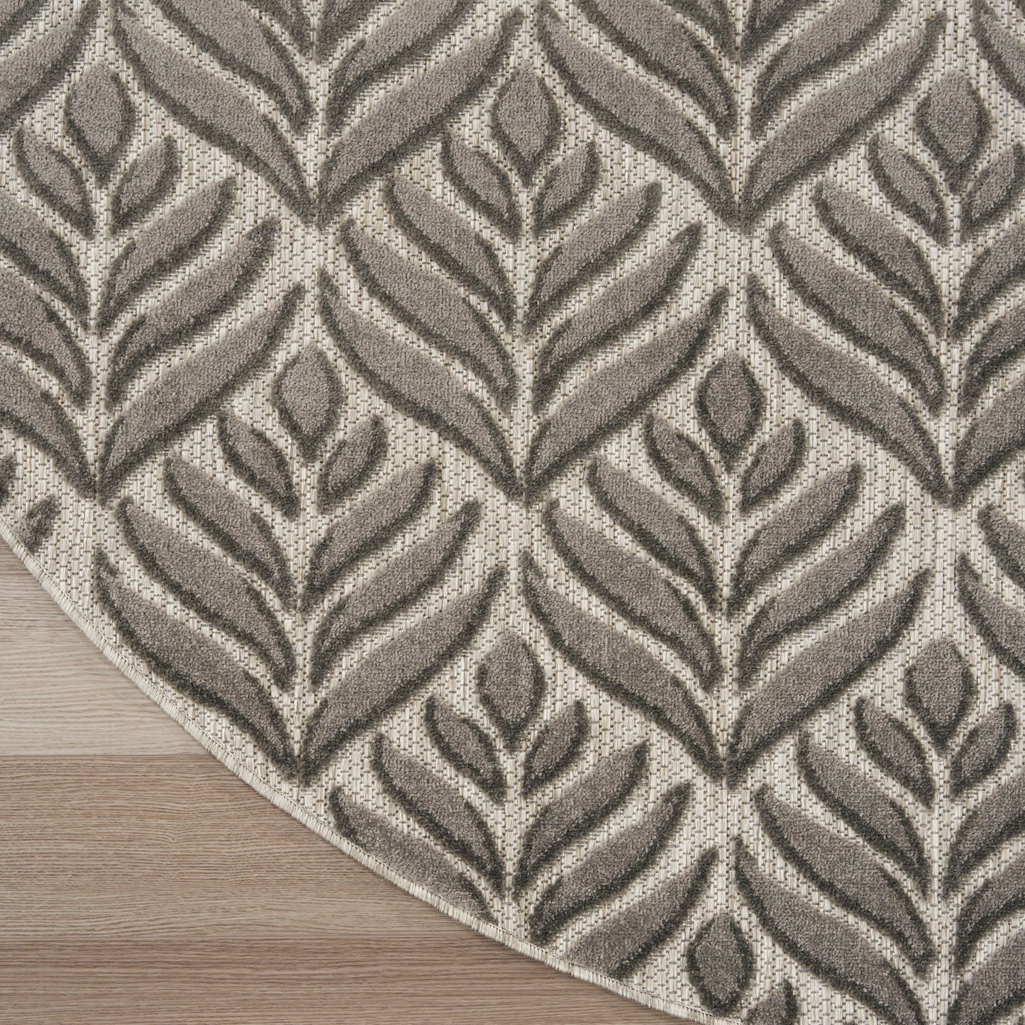 Neutral taupe and beige rug with leaf-patterned, textured fronds on a light wood floor.