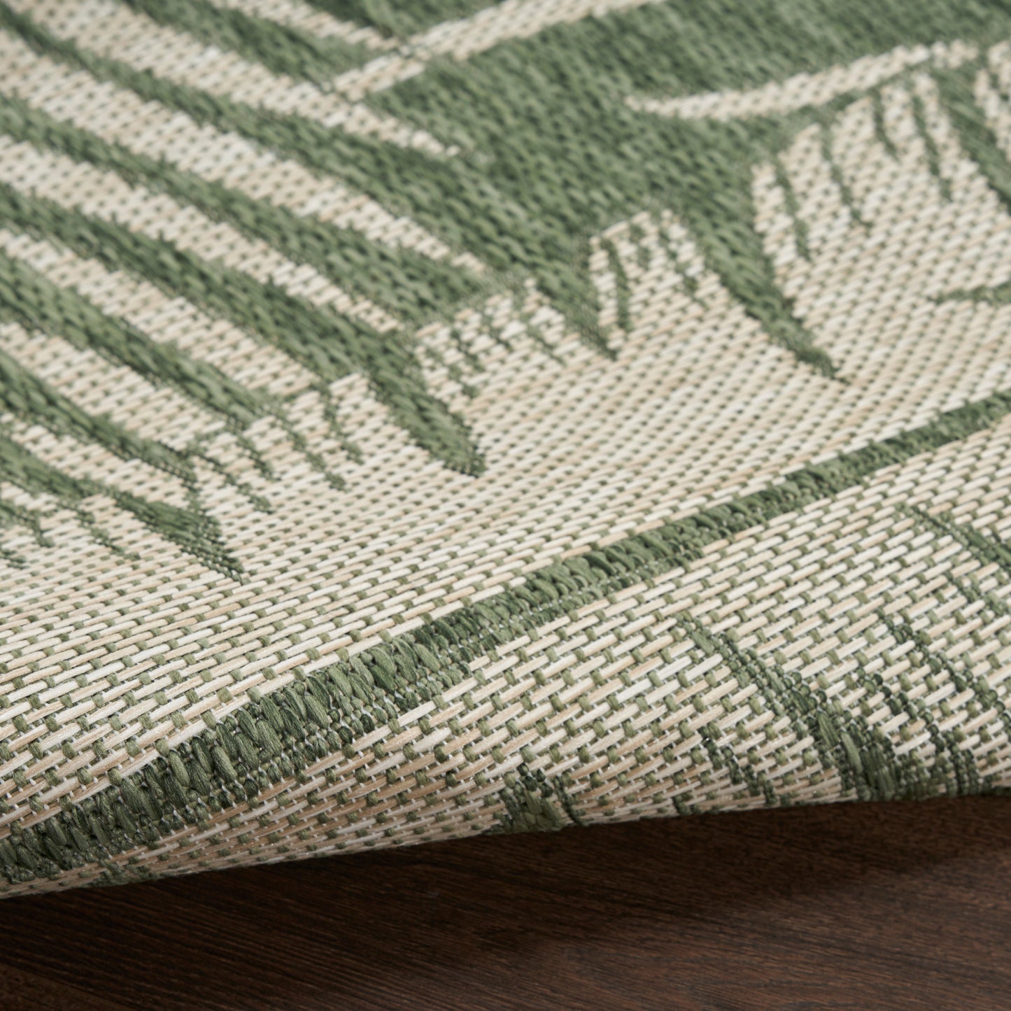 Outdoor 8' runner rug with beige and olive green palm-leaf pattern and a tight woven texture.