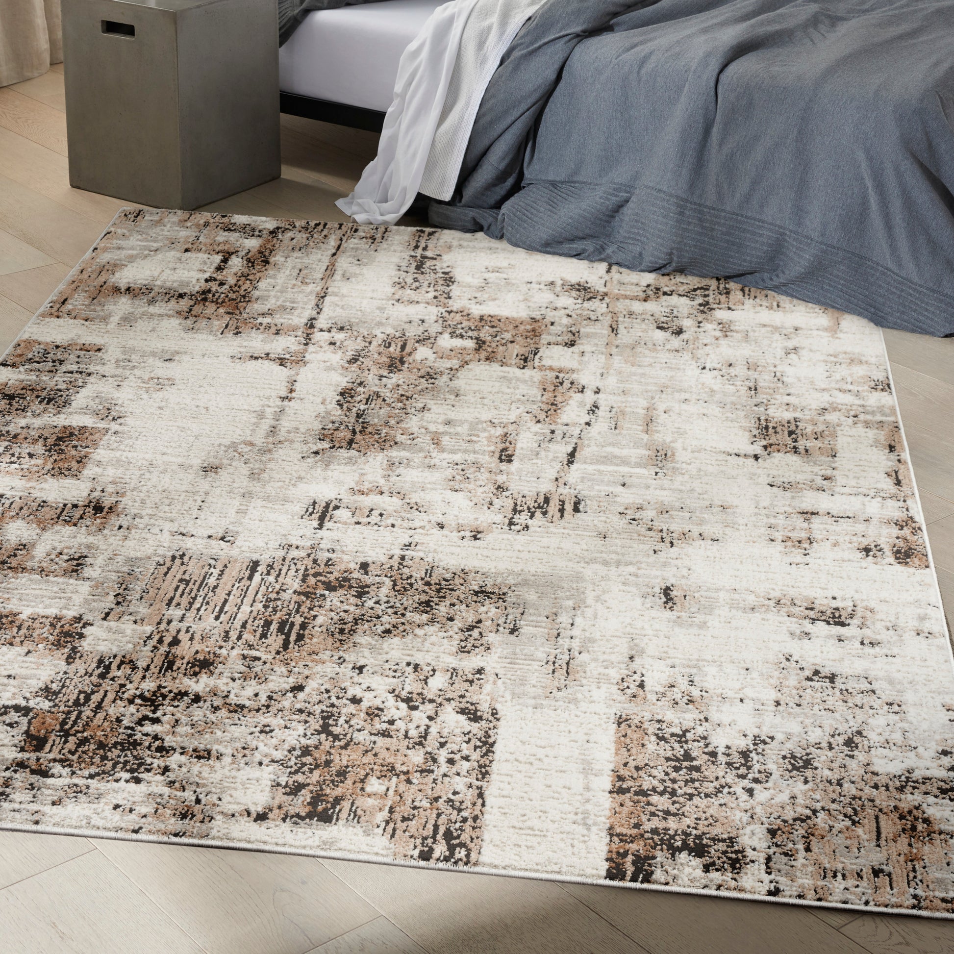 Rectangular abstract patchwork area rug in beige, taupe & brown; low-pile, modern bedroom rug under the bed.