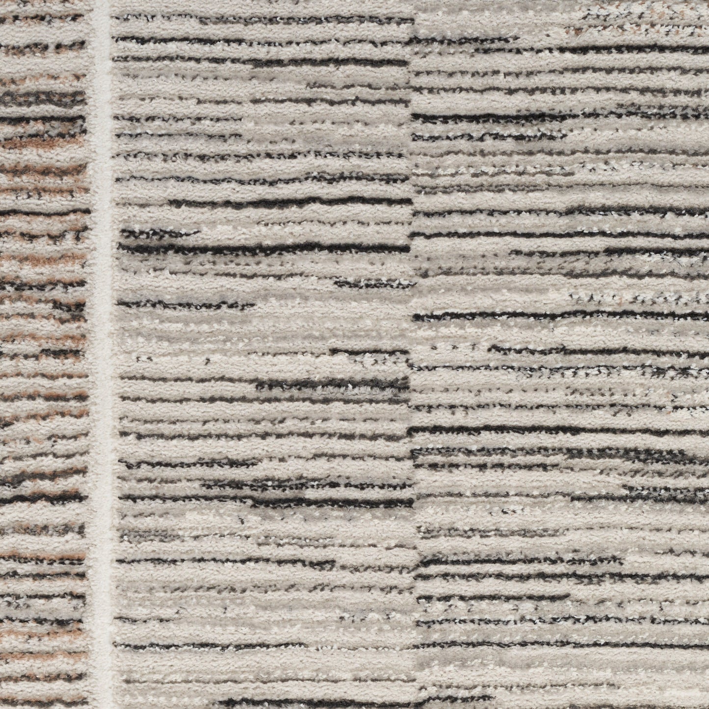 Close-up of a beige textured rug with cream and charcoal horizontal stripes and a pale vertical border.